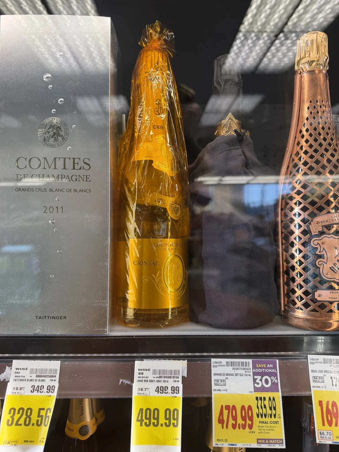Luxury Champagne bottles behind glass at Ralphs, including Cristal and Taittinger, with prices reaching nearly $500.