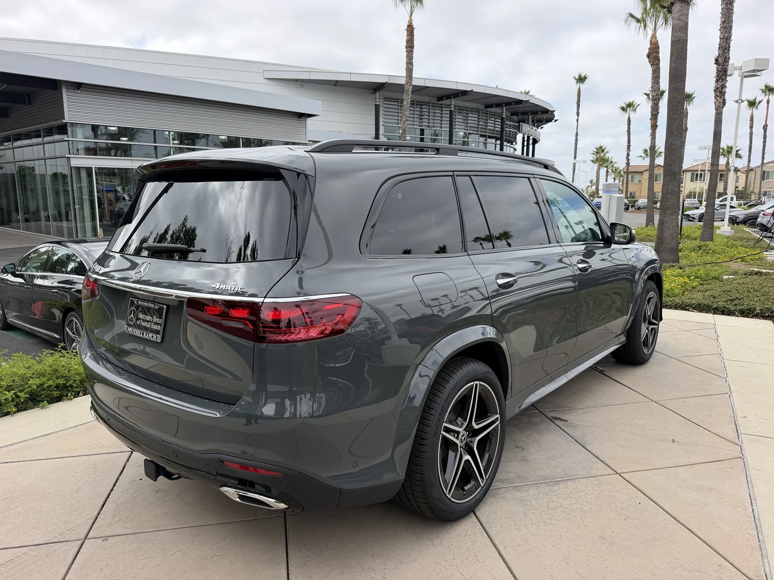 Rear three-quarter view of a gray Mercedes-Benz GLS 4MATIC SUV outside Mercedes-Benz of Foothill Ranch.