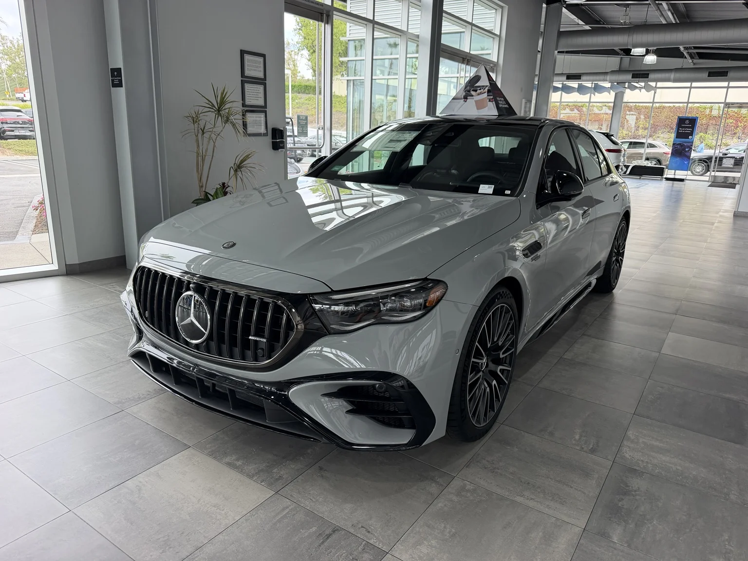 Gray 2026 Mercedes-AMG E 53 sedan photographed from the front inside the Foothill Ranch dealership showroom.