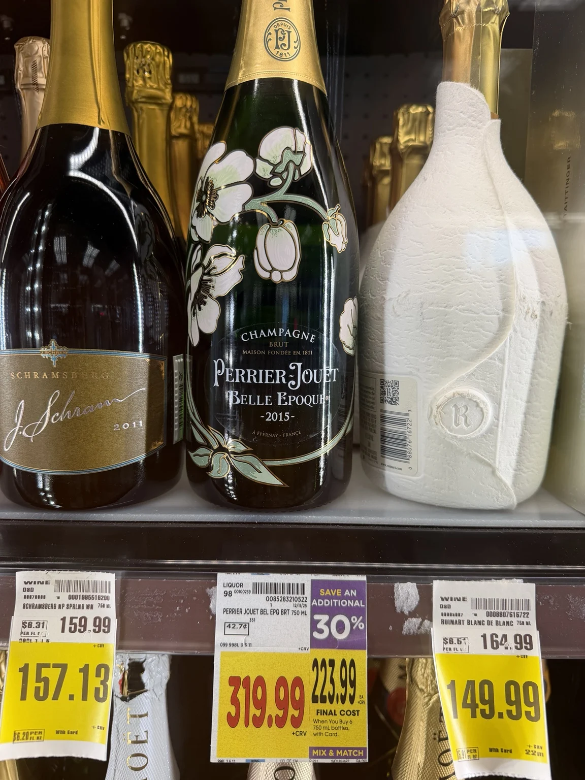 Prestige Champagne bottles at Ralphs, including Perrier-Jouët Belle Epoque and a white-wrapped Ruinart bottle.